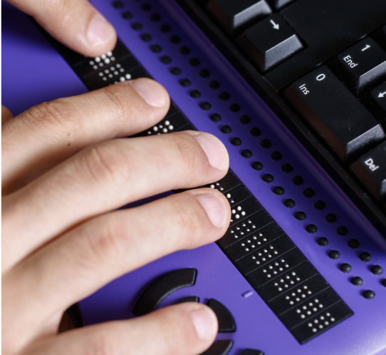 Detalhe de duas mãos utilizando um teclado braille.